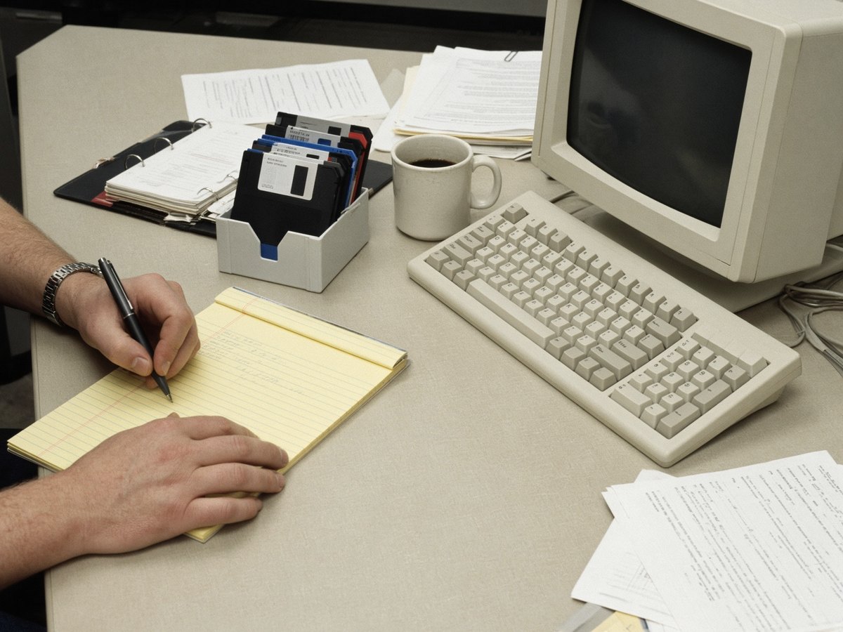 1980s desk with a legal pad, floppy disks, and a CRT.